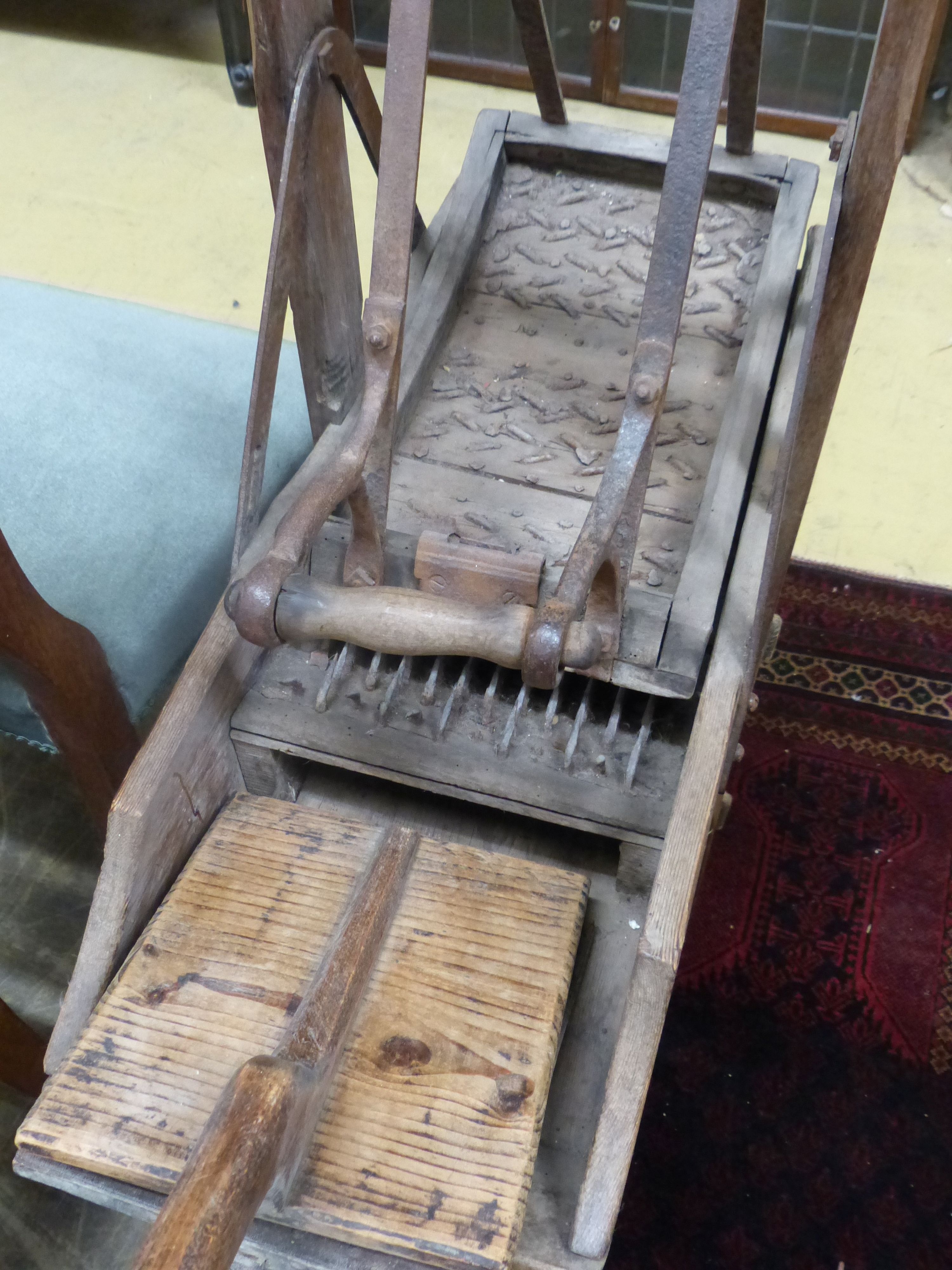 A late 19th century French Provincial (Lille) pine and wrought iron carding machine and two carding combs, length 113cm, height 120cm